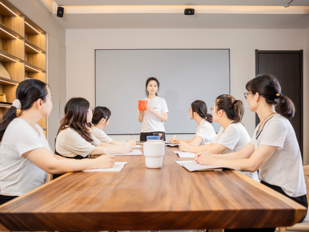A group of designers and R&D staff at a conference table, with one person presenting.