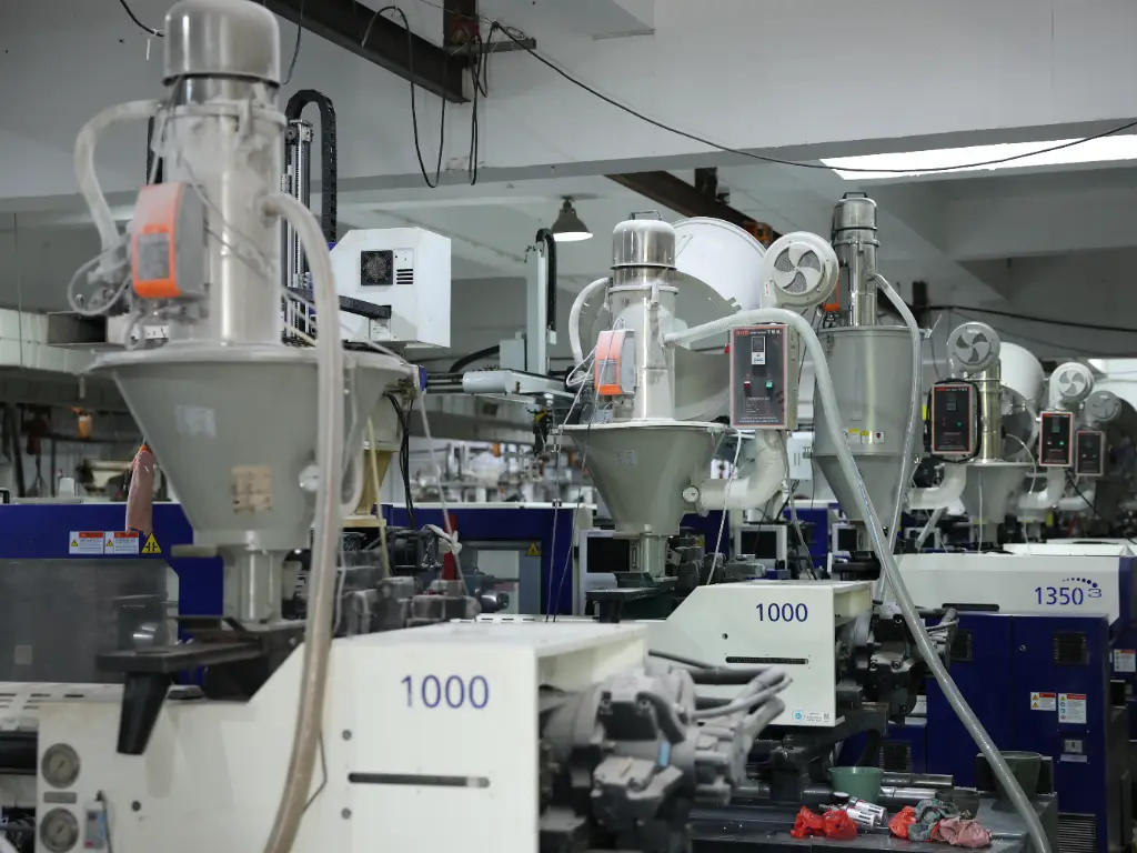 A row of industrial injection moulding machines in a factory.