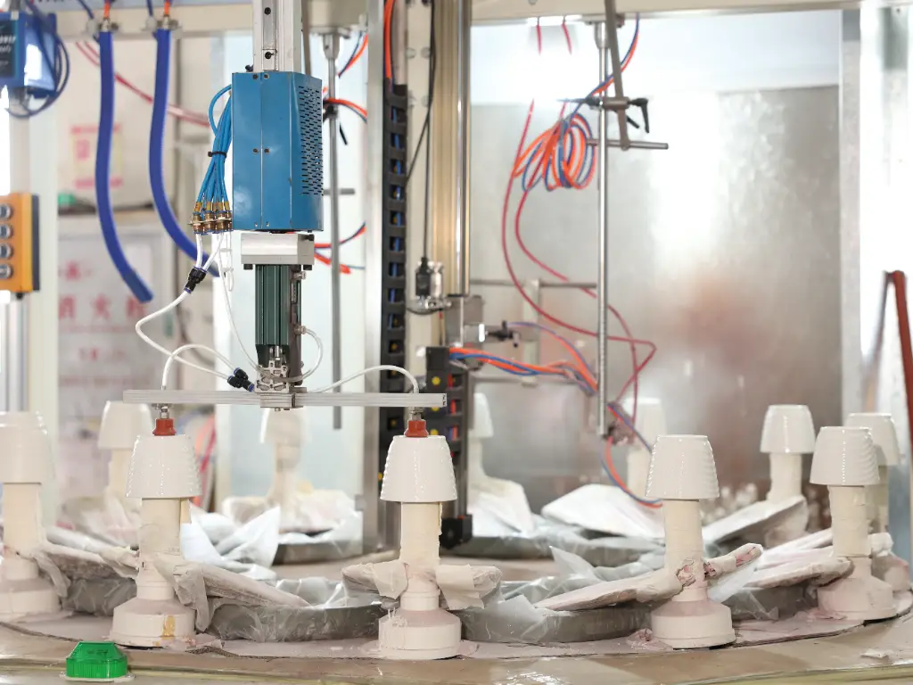 A close-up view of a machine automatically spraying coating on small flower pots.