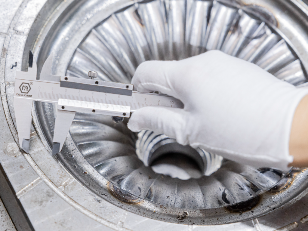 A technician in a white glove uses a caliper to measure a newly finished metal mould.