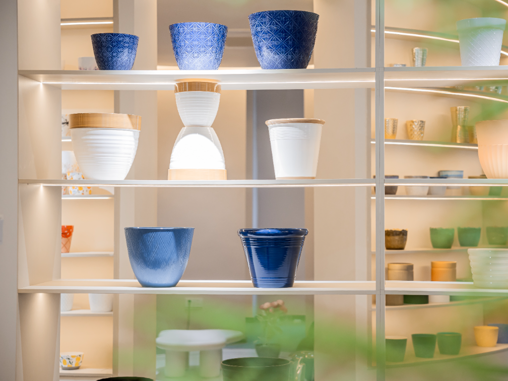 A close-up view of various modern plastic flower pots on illuminated shelves.