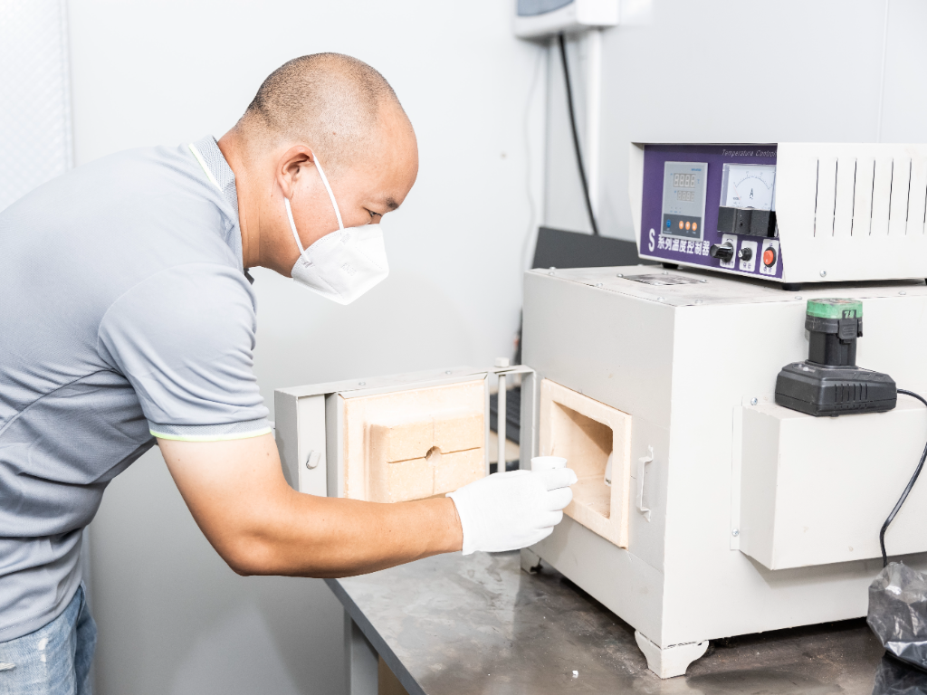 A lab technician places a sample into a high-temperature oven for a heat test.