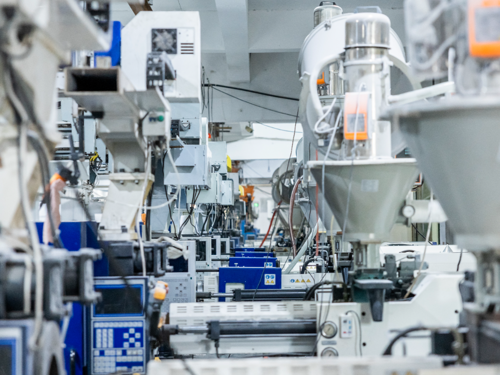 A row of large, white and blue injection molding machines.