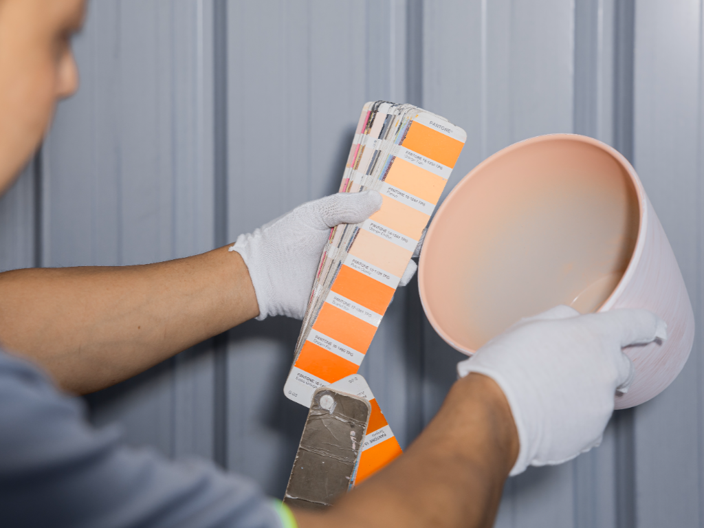 A worker in white gloves compares a plastic pot to a color swatch book.